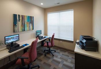 A room with a desk, chairs, and a computer monitor.